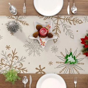 Detail of Christmas table runner with golden and silver snowflake prints on linen fabric