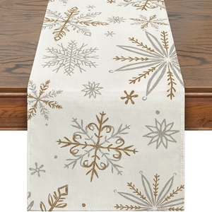 Close-up of linen table runner with gold and silver snowflake prints on dark wood