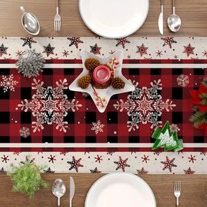 Flat lay of red and black buffalo plaid Christmas table runner with white snowflake patterns