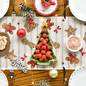 Detail of Christmas table runner featuring gingerbread man and tree on linen fabric