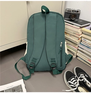 Detail view of the back of a dark green nylon business backpack with a hidden zipper pocket
