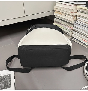 Detail of minimalist black and white canvas backpack featuring adjustable woven straps