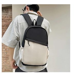 Rear view of a person wearing a two-tone black and cream waterproof nylon backpack