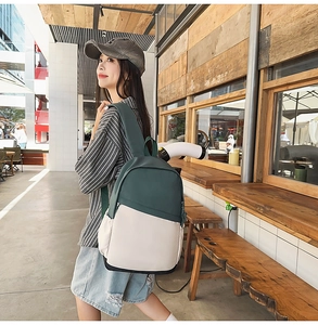 Outdoor street view of a waterproof nylon backpack in dark green and cream contrast