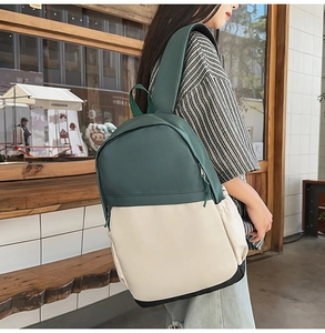 Outdoor model display of a color-block nylon backpack in dark green and cream white finish