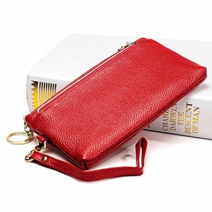 Dettaglio della pochette in pelle rossa a grana litchi con cerniera dorata e cinturino