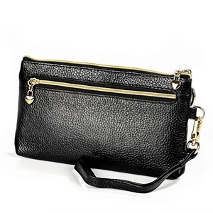 Dettaglio della pochette in pelle nera con cerniere dorate a forma di cuore e cinturino