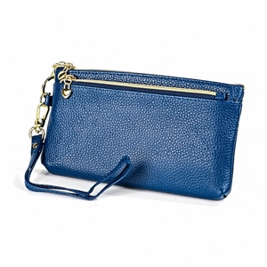 Dettaglio pelle martellata blu scuro e zip dorata a cuore su una borsa a mano compatta
