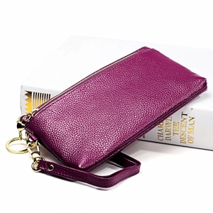 Dettaglio di pochette in pelle viola con grana litchi, zip dorata e cinturino da polso