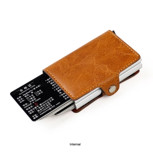 Detail of a brown lychee leather RFID card holder with a pop-up metal slot mechanism