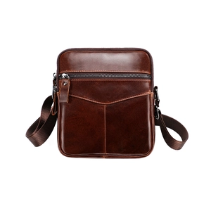 Detailed close-up of dark brown leather crossbody bag texture and front zipper pocket