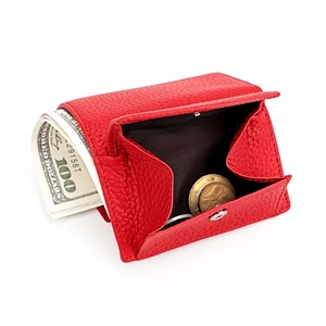Close-up of red pebbled leather wallet with coins and cash showing compact storage