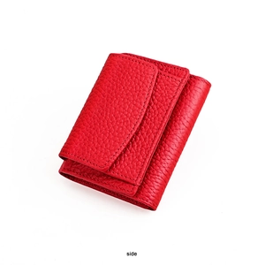 Detail of red pebbled leather wallet showing compact trifold design and fine stitching