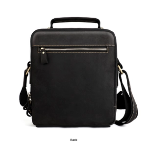 Detail view of the back leather handle and zipper pocket on a vintage crossbody bag
