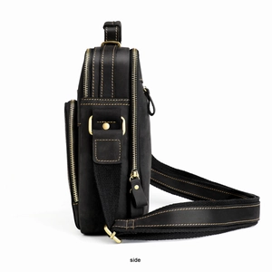 Detail of vintage black leather messenger bag featuring yellow stitching and three zippers