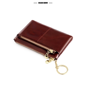 Detail of dark brown leather coin purse with gold double zippers and heart pendant