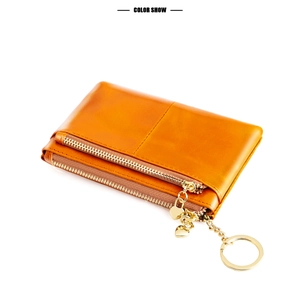 Detail view of orange oil wax leather coin purse with double zippers and heart keychain