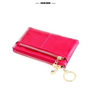 Detail of magenta leather coin purse with double gold zippers and heart charm