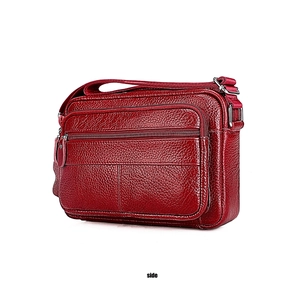 Side view detail of a genuine dark red pebbled leather shoulder bag with multiple zippers