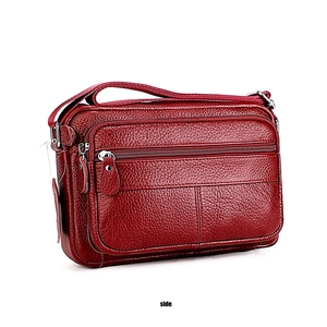 Side view of dark red leather shoulder bag with multiple zippered layers and pebbled texture