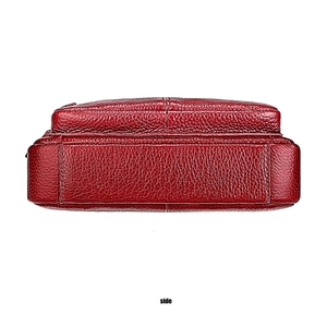 Detailed side view of red lychee grain leather shoulder bag with layered stitching