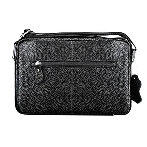 Detail of black pebbled leather texture on crossbody bag with silver zipper and tag