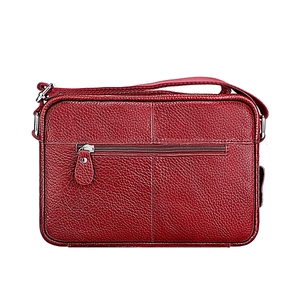 Detail of red pebbled leather shoulder bag showing silver zipper and cross stitching