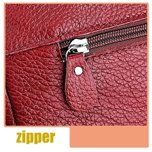 Detail of premium red litchi leather texture and silver metal zipper on a shoulder bag