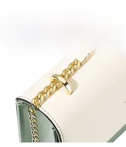 Détail de la bandoulière en chaîne dorée et du coussinet en cuir sur le sac