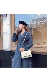 Photo street style d'une femme avec un sac à chaîne crème et vert et un trench-coat gris