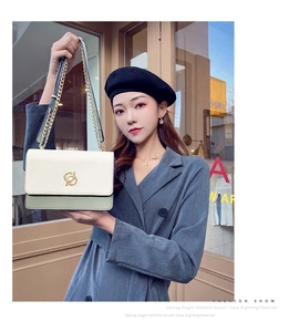 Détail d'un sac bandoulière chic crème et vert avec une bandoulière chaîne dorée