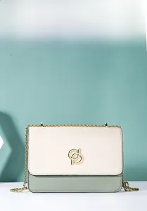 Détail du sac bandoulière beige et vert avec logo doré et bandoulière en chaîne