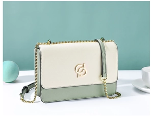 Détail du sac bandoulière bicolore avec emblème doré et coutures en cuir raffinées