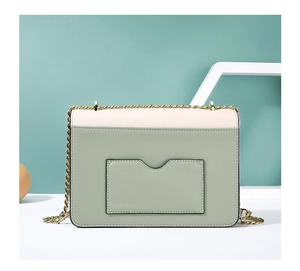 Détail d'un sac en cuir texturé avec fente pour cartes et bandoulière en chaîne dorée