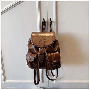 Detalle de mochila vintage de cuero marrón con bolsillos de hebilla y piezas metálicas