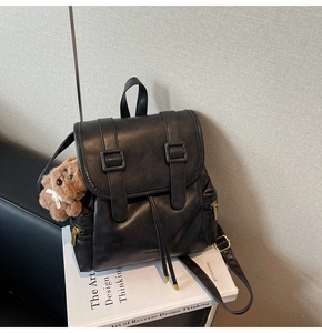 Detail of black faux leather backpack with drawstring closure and brown bear charm