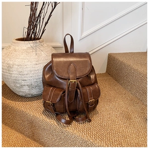Detalle de mochila vintage de cuero marrón con hebillas y dos bolsillos frontales