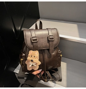 Detail of dark coffee vintage backpack featuring leather straps and plush puppy charm