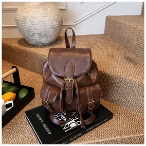 Detalle de mochila vintage marrón oscuro con dos bolsillos frontales y cierres de hebilla