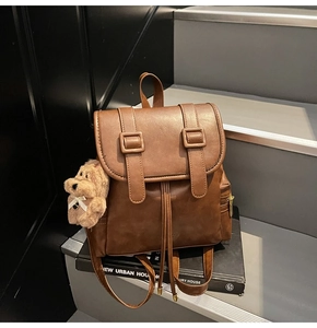 Detail of brown leather backpack with drawstring closure and cute plush dog charm