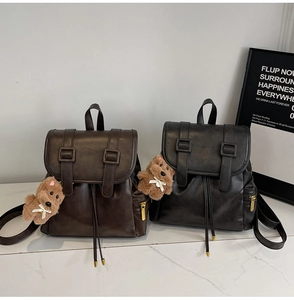 Detail of vintage faux leather backpacks with buckle straps and plush bear charms