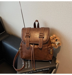 Close-up of brown vintage leather backpack with drawstring closure and cute bear charm