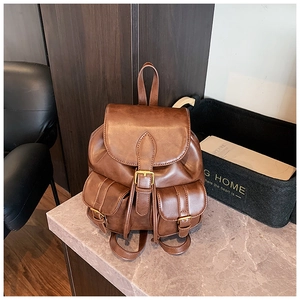 Detalle de la mochila vintage de cuero marrón con bolsillos de hebilla y asa superior