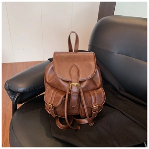 Primer plano de mochila vintage de cuero marrón con hebillas metálicas y cordón