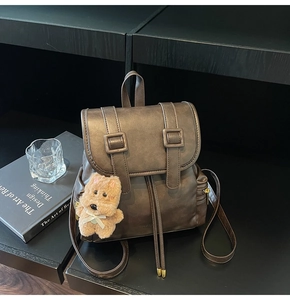 Detail of vintage brown PU backpack featuring drawstring closure and decorative buckle straps