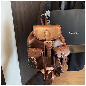 Primer plano de mochila retro en cuero marrón con hebillas de metal y acabado texturizado