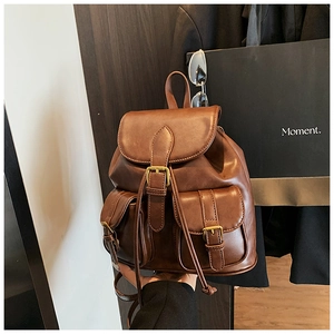 Detalle de mochila vintage marrón oscuro con hebillas metálicas doradas y solapa