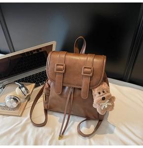 Detail view of brown vintage leather backpack with drawstring and plush puppy charm