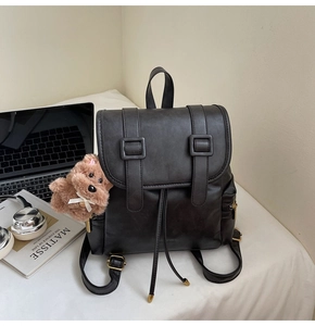Close-up of black retro PU leather backpack with drawstring closure and cute bear charm