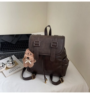 Close-up of vintage brown leather backpack with drawstring, metal buckles and dog charm